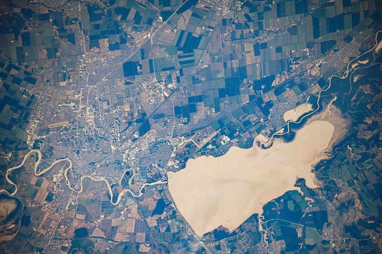 Снимок Краснодара с орбиты демонстрирует городские кварталы, реку Кубань, поля и водохранилище, а также часть территории Республики Адыгея.